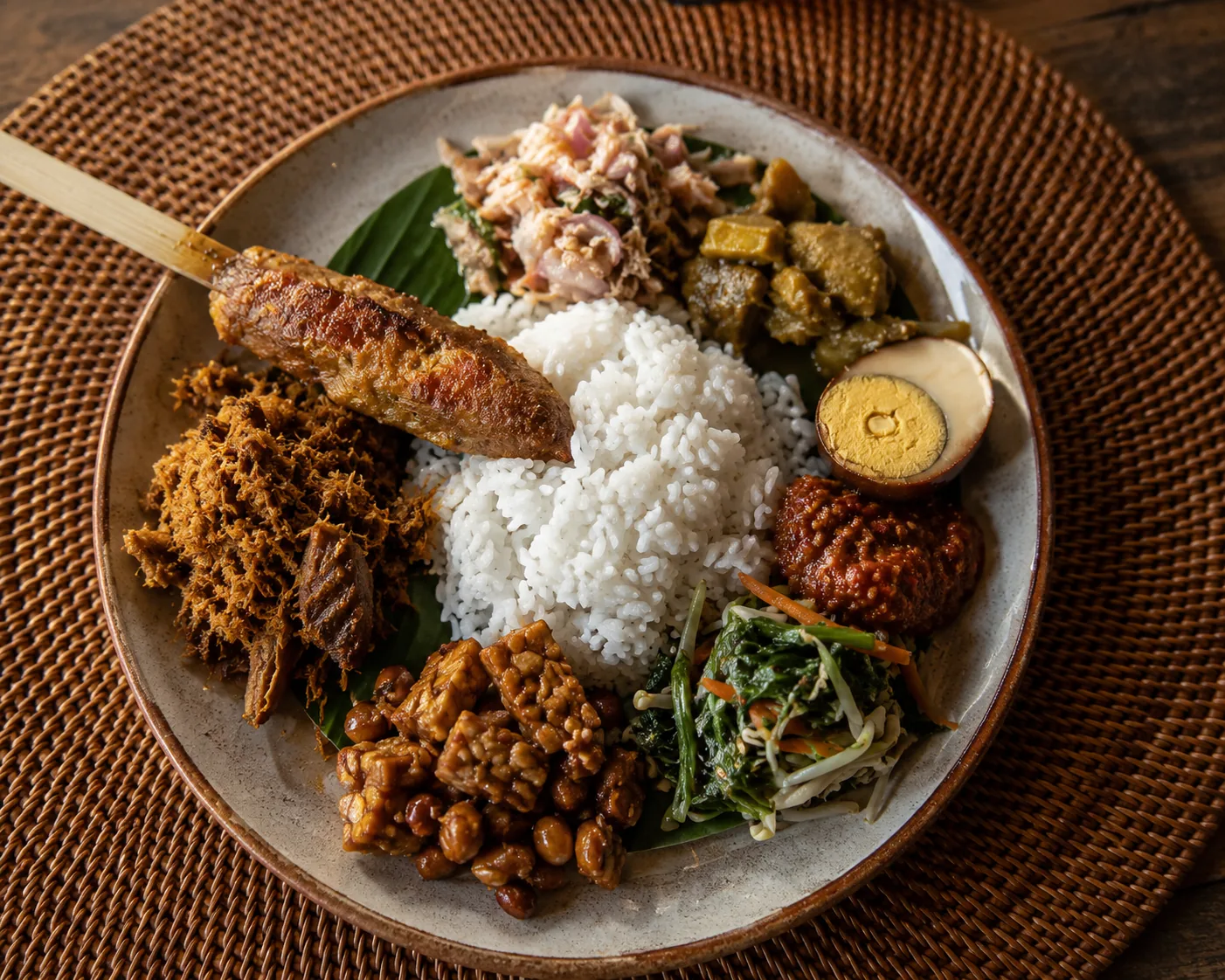 Nasi campur plate with sate lilit, sambal, egg, and vegetables